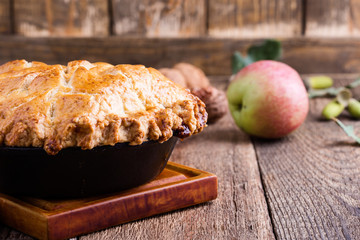 Apple pie in cast iron skillet on rustic wooden table