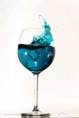 Blue curacao drink splashing on the right side of the glass