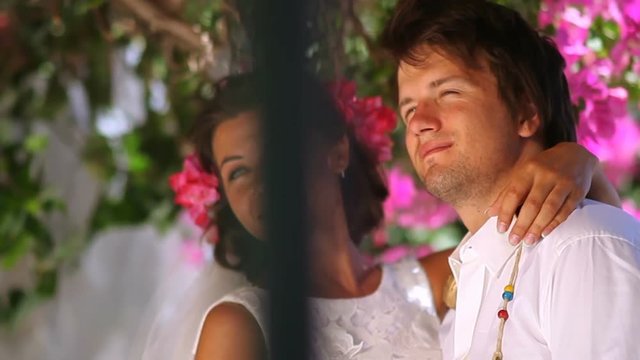 Beautiful bride and groom sit on the steps against the background of flowers Greece. slow motion. Wedding day.
