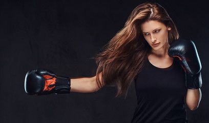 Beautiful brunette female boxer during boxing exercises, focused on a process with serious concentrated facial.