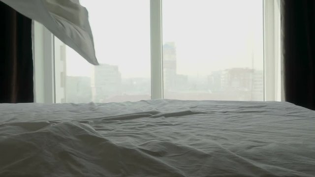 Making bed in high rise apartment bedroom in the morning