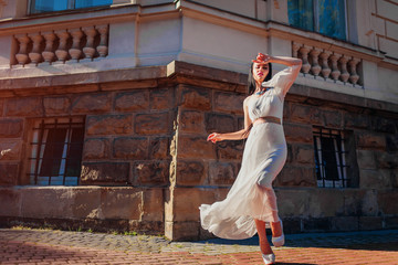 Beautiful fashion model posing in white wedding dress outdoors. Young woman wearing accessories and jewellery