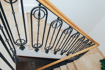 Fototapeta na wymiar Spiral staircase with wooden railing, marble steps and wrought iron balusters, top view.