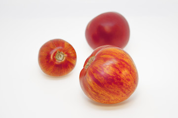 Motley tomatoes and red tomato with unusual natural pattern. A beautiful unusual three tomatoes, in front of white background. 