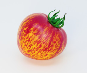 Motley tomato with unusual natural pattern. A beautiful unusual tomato with a green tail, in front of white background. 