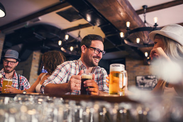 Happy friends having fun at bar - Young trendy people drinking beer and laughing together