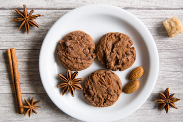 Tasty  chocolate cookies, anise stars spices, brown sugar and cinnamon rolls on wooden background, top view. Winter Christmas mood.
