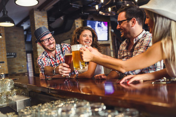 Happy friends having fun at bar - Young trendy people drinking beer and laughing together
