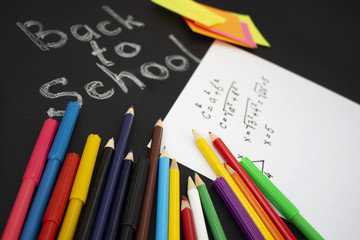Back to school flat lay. Colour pencils, stickers and lesson notes on black background