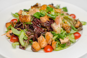 salad with fried red fish with greens and tomatoes on a white plate. a useful dietary dish. fresh delicious salad
