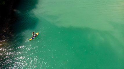 vue aérienne sur une personne debout sur un stand up paddle jaune sur des eaux vertes 