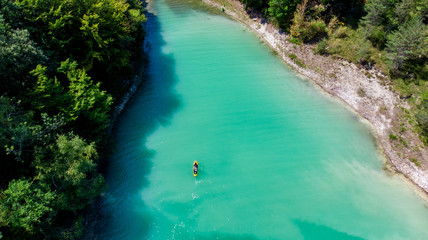 vue aérienne sur un lac aux eaux vertes émeraudes avec une personne sur un stand up paddle
