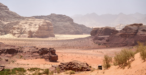Adventures safari jeep car in Wadi Rum desert, Jordan, Middle East, known as The Valley of the Moon. Red sands, sky with haze. Designation as a UNESCO World Heritage Site.