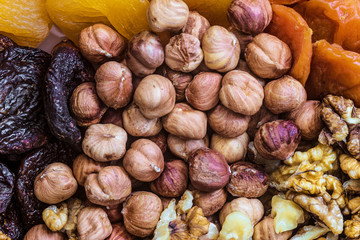 Peeled hazelnuts in a grocery set amid walnuts kernels and dried apricots