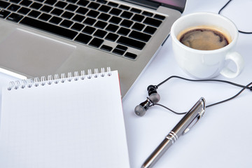 Modern white office desk table with laptop computer, notebook, pen, cup of coffee and earphone. Top business view. Top view with white background.