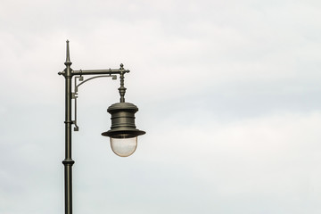 Black metal vintage street lamp on a cloudy sky background. Background with copy space.