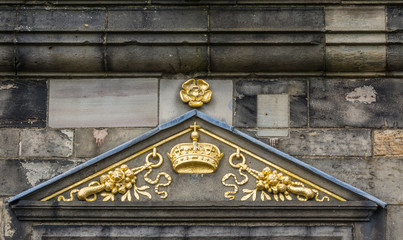 Edinburgh, Scotland, UK - June 14, 2012: Closeup of golden Royal symbols such as a crown, rose and a cross, on black and gray stone building at Castle.