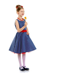 A little girl licks lollipop.