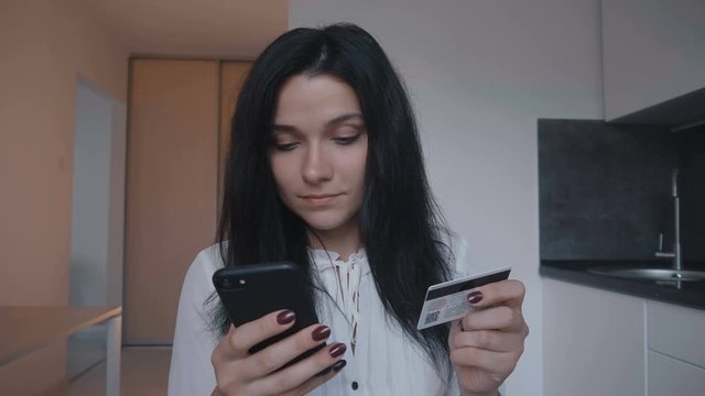 Young woman shopping online with credit card and smartphone at home