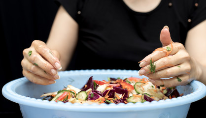 Obraz na płótnie Canvas woman preparing salad with fresh vegetables. Preparation of tasty and healthy food on a black background