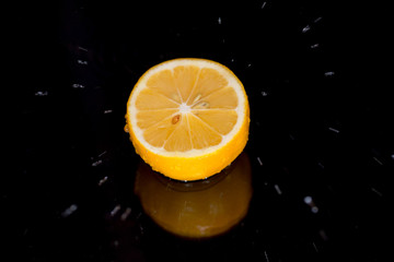 Splashing water against a tasty lemon on a black background