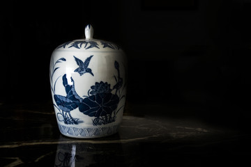 Antique Chinese porcelain jar in an auction against a black background. Empty copy space for Editor's text.