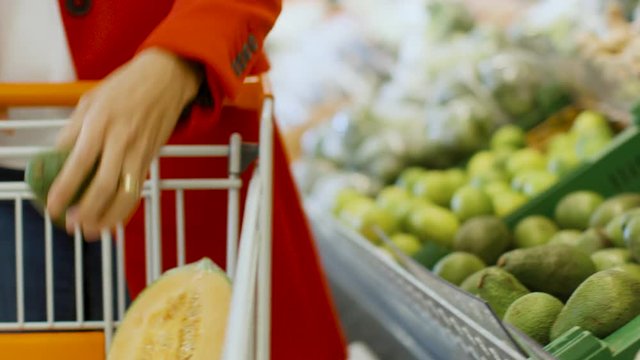 At the Supermarket: Close-up Shot of the Woman's Hand Taking Avocado from the Fresh Produce Section and Places it into Shopping Cart.