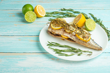 Cooked mackerel on a white plate with spices, herbs, lemon, lime and salt. Top view, space for...