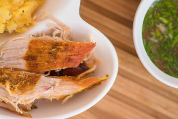 Close up of typical Andean food hornado inside of a white plate with mashed potatoes with salad