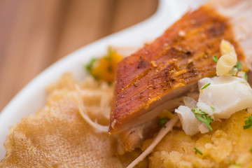 Close up of homemade mashed potatoes with salad, tostado, mote and sliced pieces of hornado