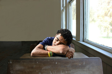 Young Guy Sleeping At A Desk In A Classroom