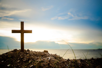 The cross standing on meadow sunset and flare background. Cross on a hill as the morning sun comes up for the day.The cross symbol for Jesus christ.Christianity, religious, faith, Jesus or belief.