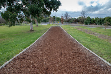 Shredded bark chip mulch provides a safe landing area for children under a flying fox in a...