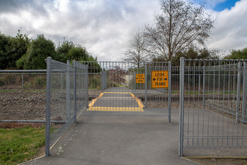 Barriers, yellow lines and signs at a pathway across a train track or railway line for public safety