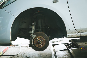 brake and detail of the wheel hub. car brake pads.disc brakes on cars in process of new tires replacement in the garage or auto repair service center, as background automotive concept.