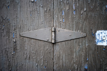 A hinge on an old door that has many layers of paint