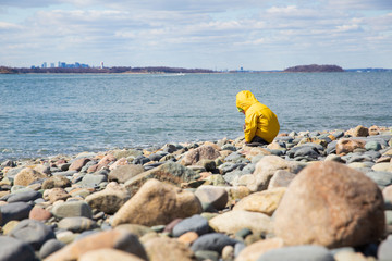 kid playing on the rocky shore. child curiously looking at stones on the beach. Copy space for your text