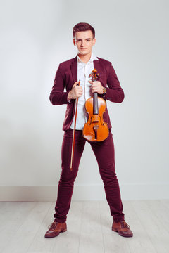 Young man holding violin and fiddlestick