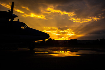 Fototapeta na wymiar Modern airplane silhouette at sunset on the ground