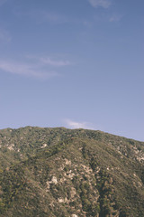 Green mountain top with vegetation and blue sky above