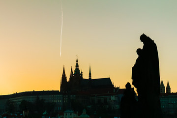 Vista panorámica de un atardecer sobre el Puente de Carlos en Praga. Silueta de las estatuas en primer plano y cómo fondo la silueta de la catedral de la ciudad. 