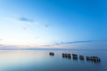 smooth sea surface and breakwaters in blue twilight on long exposure
