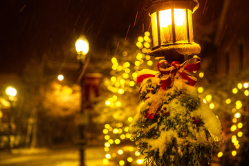 street lamp with Christmas decorations under the snow. White Christmas. spruce branches and a red...