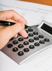 Close-up of a Businessman Using Calculator with Financial