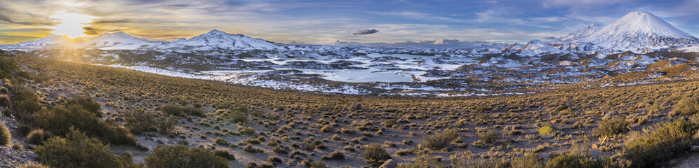 The great "Nevados de Payachatas" with the Pomerape and Parinacota Volcanoes, left and right respectively over the Atacama desert meadows during sunset an amazing colorful landscape, Arica, Chile