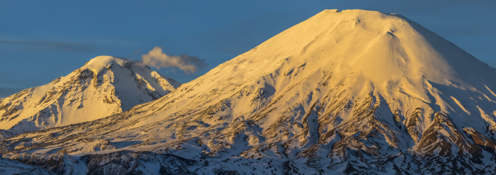 The great "Nevados de Payachatas" with the Pomerape and Parinacota Volcanoes, left and right respectively over the Atacama desert meadows during sunset an amazing colorful landscape, Arica, Chile