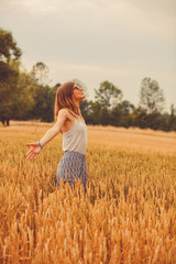 Girl enjoying in a golden wheat - field in the summer.