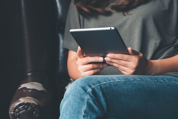 Closeup image of a woman holding and using tablet pc in modern cafe