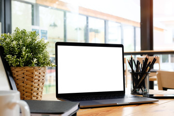 Mockup laptop computer on wooden table in office workspace.