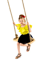 Joyful little girl swinging on a swing.